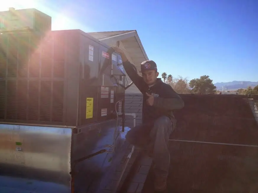 HVAC technician performing AC Tune-Up on a rooftop unit in Logan